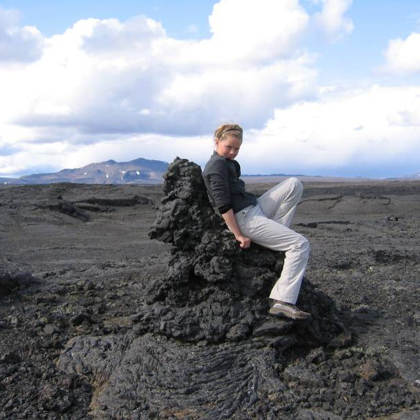 Nanna Björk sitjandi á drýli sem er skammt frá hellisopinu.