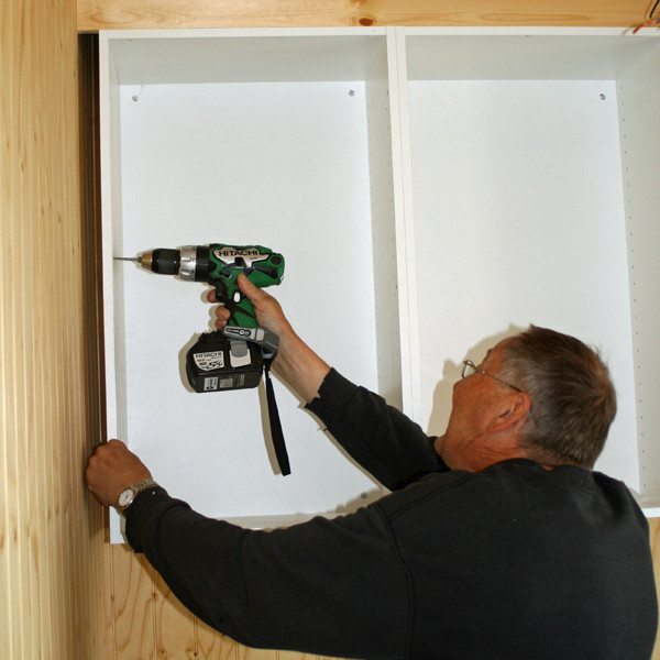 Hilmar að festa upp skáp í eldhúsi Þórunnarbúðar.