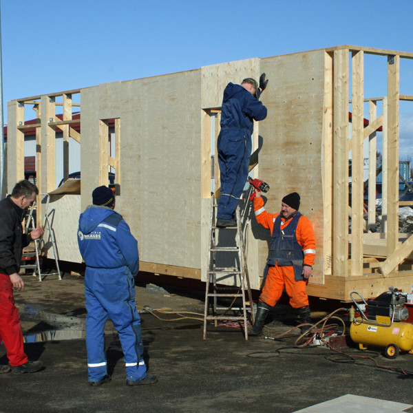 Vignir og Einar stilla krossviðarplötu af á vegg skálans.