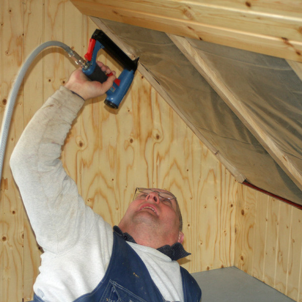 Einar að setja hefti í panelklæðningu á súð.