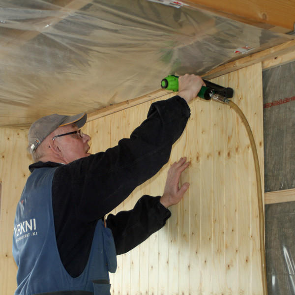 Atli að festa þilplötu með heftibyssu.