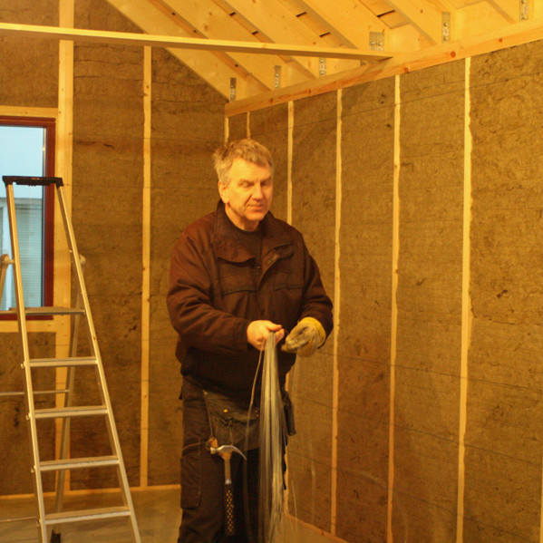 Grímur Laxdal að festa vír yfir steinull í veggjum skálans