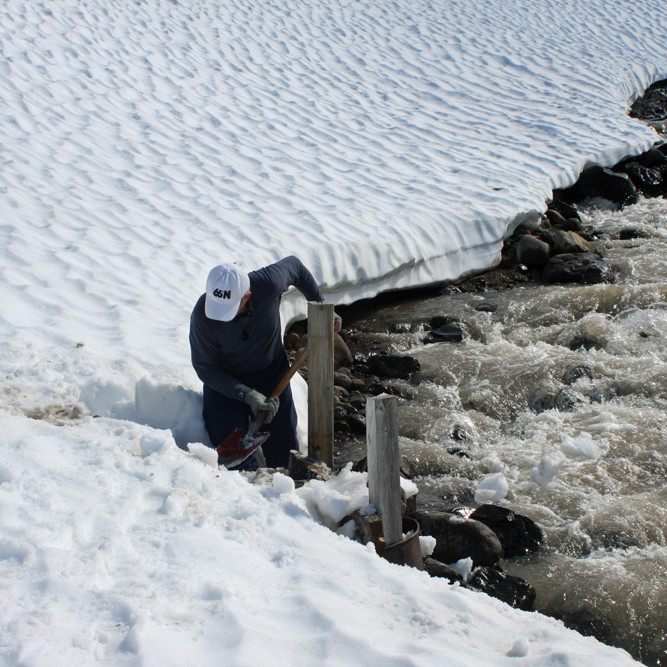 Snjó mokað ofan af undirstöðum brúarinnar norðan ár.