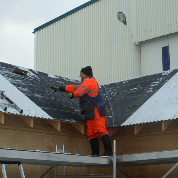 Einar Hjartarson að sópa snjó af þaki Nýja-Lamba.