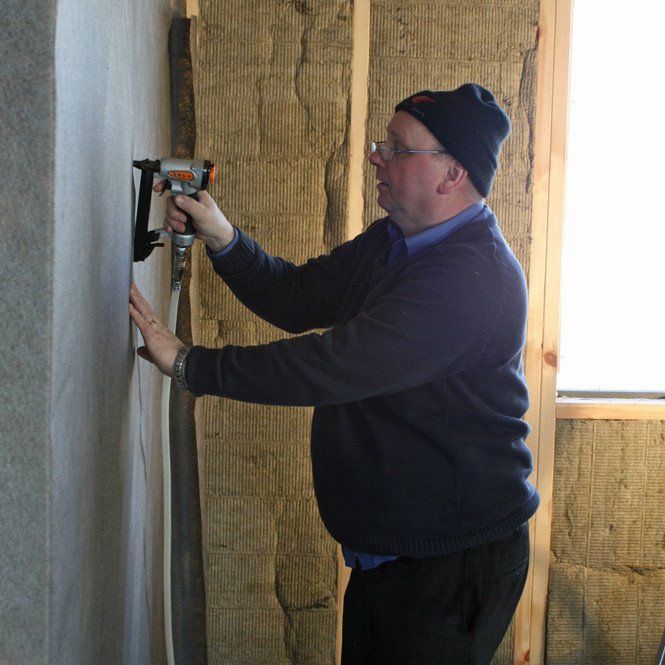 Þorvaldur að festa dúk innan á vegg skálans.