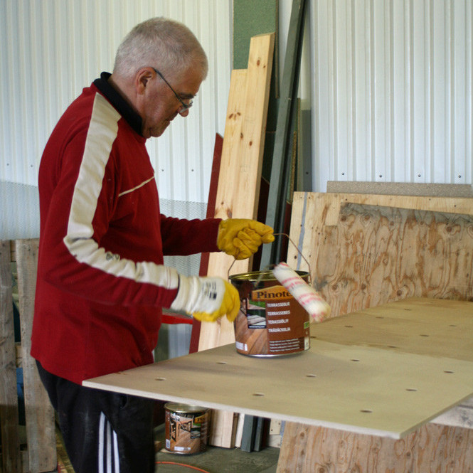 Villi Agnarss að olíubera krossvið í kojubotn.